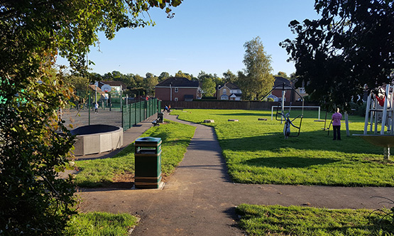 a beautiful field with trees wither side, a tennis court and a childrens play park